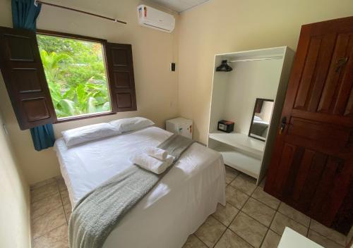 a bedroom with a bed with a window and a mirror at Pousada Alto da Praia in Arraial d'Ajuda