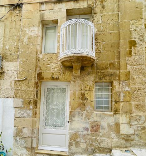 a building with a white door and a balcony at La Bambina in Senglea