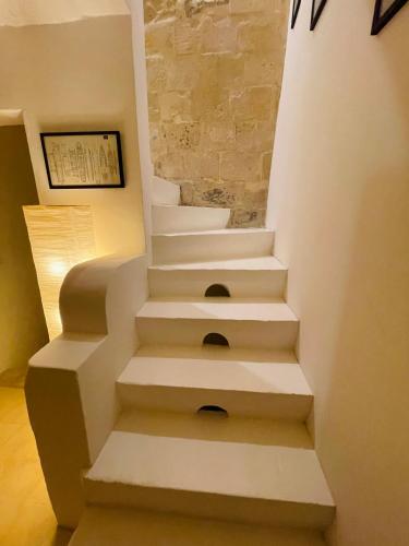 a white staircase in a room with a stone wall at La Bambina in Senglea
