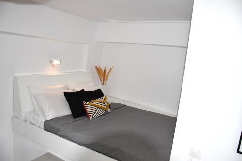 a bed in a white room with pillows on it at Amelia in Kavoúsion