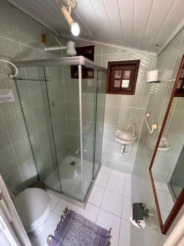 a bathroom with a shower and a toilet and a sink at Pousada Cachoeira in Abraão