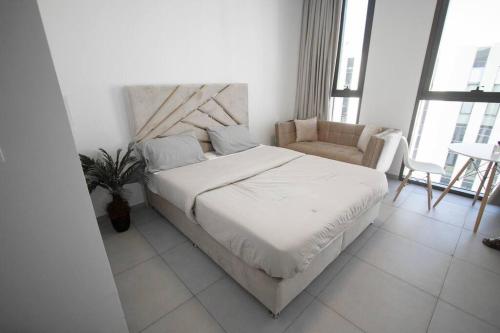 a white bedroom with a bed and a chair at 20 Mins drive to Dubai International Airport in Sharjah