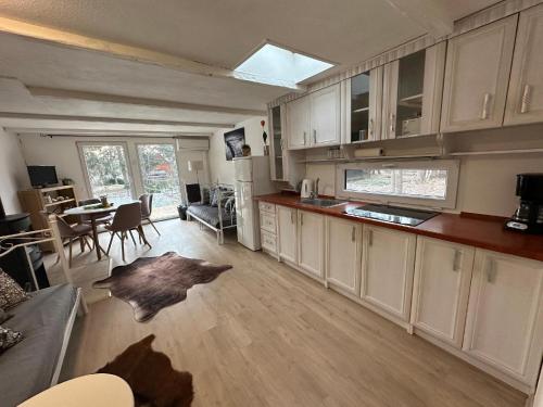 une cuisine avec des placards blancs et un salon avec une table dans l'établissement Beach House Buxusson Resort, à České Budějovice