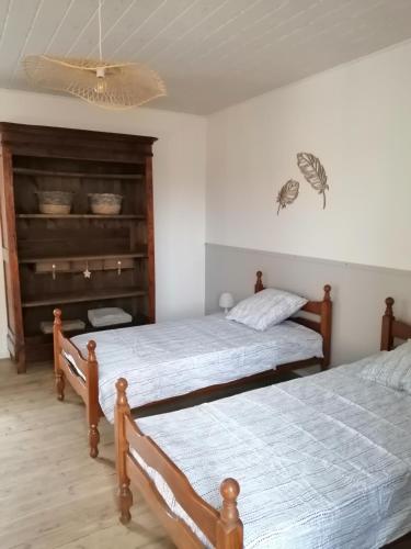 a bedroom with two beds and a chandelier at La Maison des Rosiers in Manhac