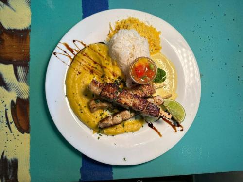 a plate of food with meat and rice on a table at Pousada dos Gravatás in Búzios
