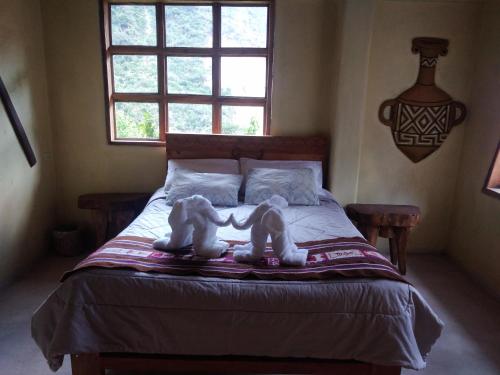 dois bichos de peluche sentados em cima de uma cama em Salkantay Hostel Chaullay em Santa Teresa