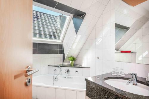 a bathroom with a tub and a sink and a window at Hotel Garni Dorfkammer in Olsberg