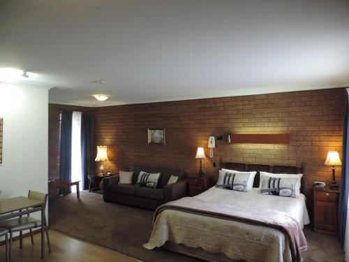 um quarto com uma cama e uma parede de tijolos em Greenacres Motel em Corowa