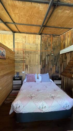 a bedroom with a bed in a wooden room at Cabaña de la nona in Futaleufú