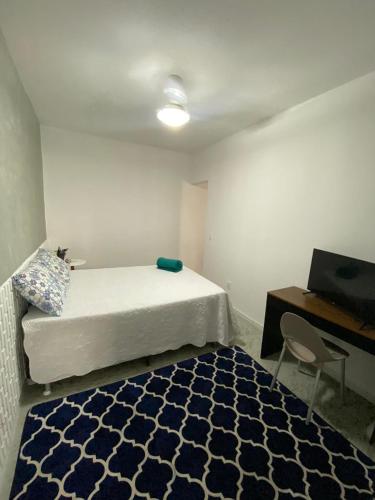 ラウロ・ジ・フレイタスにあるSuítes Vilas do atlântico a 100M da praiaのベッド、デスク、ベッド、ラグが備わる小さな客室です。