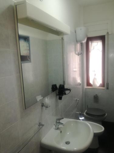 a bathroom with a sink and a toilet and a mirror at Affittacamere da chris in Reggio Calabria