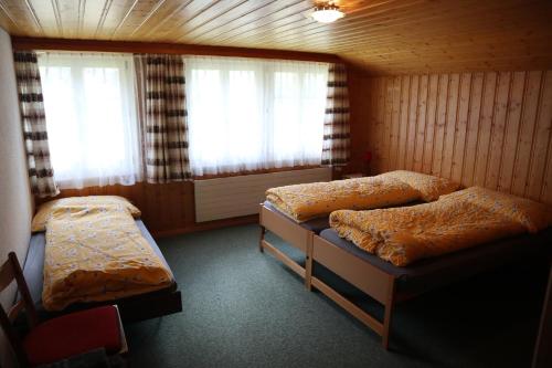 a bedroom with two beds and two windows at Gasthaus Bergheim in Gurtnellen