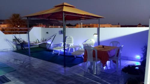 une terrasse avec une table, des chaises et un parasol dans l'établissement Perle d'Azur F3, à Saïdia