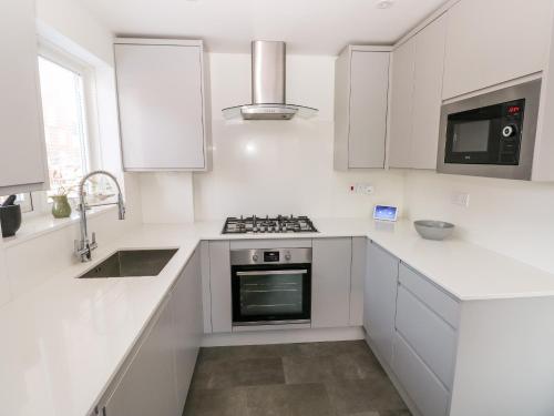 a white kitchen with a stove and a sink at 12 Clos Yr Wylan in Barry