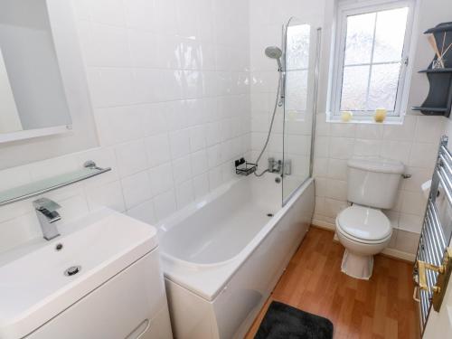 a white bathroom with a toilet and a tub and a sink at 12 Clos Yr Wylan in Barry