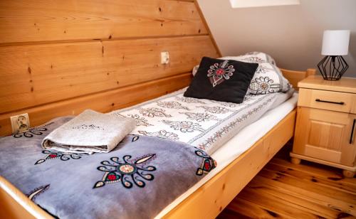1 cama con cabecero de madera y almohadas en HRYCÓWKA Domki z Widokiem, en Grywałd