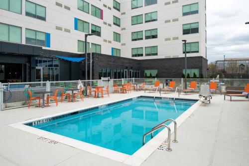 a swimming pool with orange chairs and a building at Aloft Tulsa in Tulsa