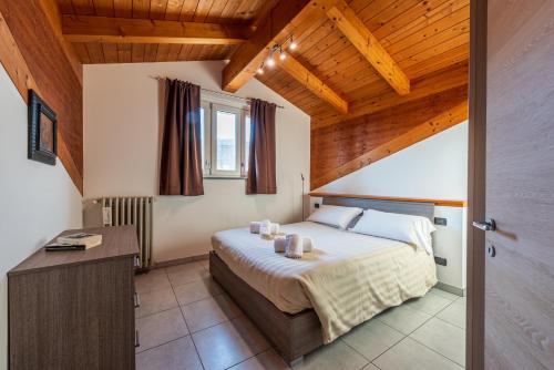 una camera con letto in una stanza con soffitti in legno di In Piazzetta holiday apartments, Barolo a Barolo