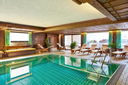 a swimming pool in a room with chairs and tables at Kurhotel Eichinger in Bad Wörishofen