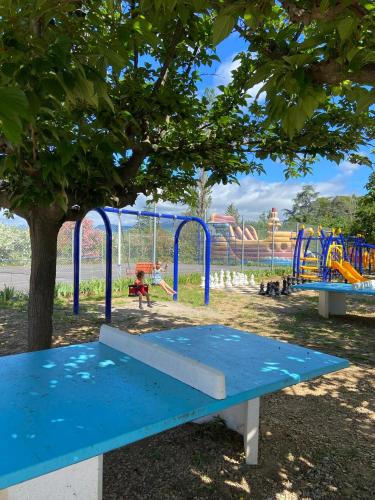 un banc bleu dans un parc avec une aire de jeux dans l'établissement Camping Paradis Family les Rives de l'Hérault, à Gignac