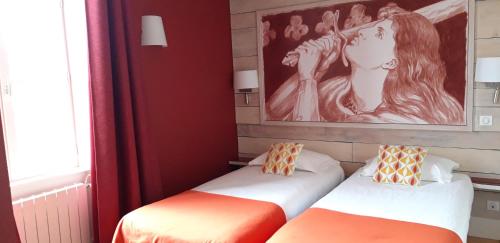 two beds in a room with a painting on the wall at Logis hôtels Auberge du Château in Saint-Rémy-de-Blot
