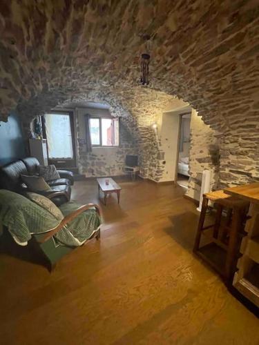 un salon avec un canapé et un mur en pierre dans l'établissement charmante cave voûtée 4 personnes, à Saint-Jean-de-Fos