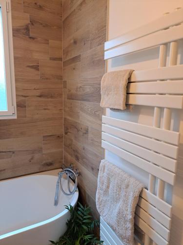 een badkamer met een wit bad en houten wanden bij Chambre indépendante en forêt in Plessé