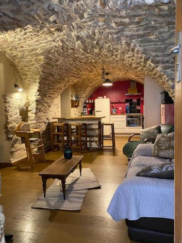 un salon avec une table et un mur en pierre dans l'établissement charmante cave voûtée 4 personnes, à Saint-Jean-de-Fos