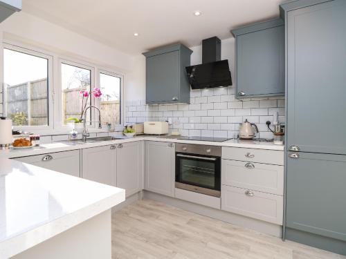 a kitchen with white cabinets and blue appliances at 1 Star Cottages in Freshwater