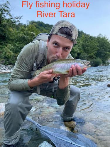a man holding a fish in a river at Mountain Mirage in Mojkovac