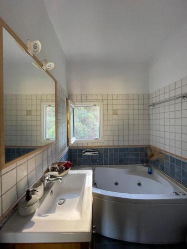 a bathroom with a tub and a sink and a mirror at Gialos Villas 1-2 in Mikros Gialos
