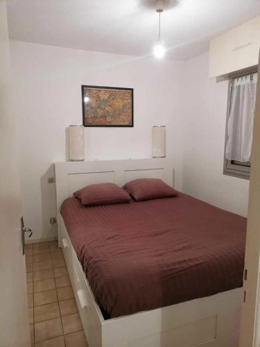 1 dormitorio con 1 cama en una habitación blanca en T2 lumineux avec jardinet - Barbotan les Thermes, en Barbotan-les-Thermes