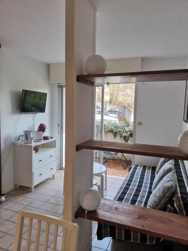 - un salon avec une table et un bureau avec un ordinateur dans l'établissement T2 lumineux avec jardinet - Barbotan les Thermes, à Barbotan-les-Thermes