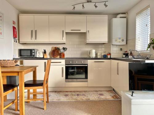 a kitchen with white cabinets and a table and a table and chairs at Seascape Stay No 4, Sea View & Parking in Falmouth
