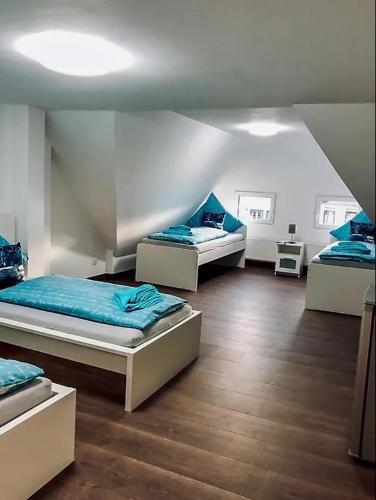 a room with three beds with blue sheets and wooden floors at Ring Home Stay in Adenau