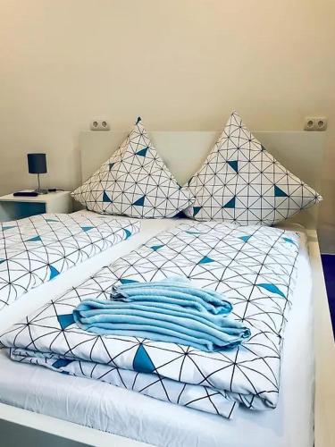 a bed with blue and white sheets and pillows at Ring Home Stay in Adenau