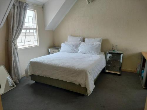 a bedroom with a bed with white sheets and a window at Neatly Furnished Apartment in Mataffin