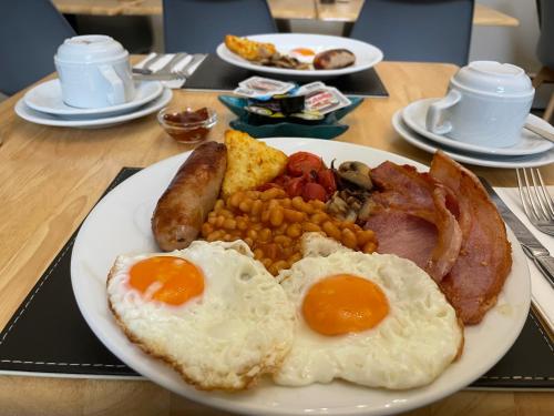un plato de comida para el desayuno con huevos, salchichas, frijoles y tocino en Babbacombe Palms, en Torquay