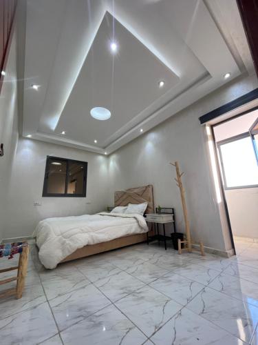 ein Schlafzimmer mit einem Bett und einem Tisch auf einem Fliesenboden in der Unterkunft Dar MAKTOUBE in Mohammedia