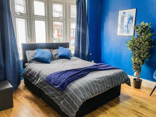 Schlafzimmer mit blauen Wänden und einem Bett mit blauen Kissen in der Unterkunft Equires East London Townhouse by Harlington in London