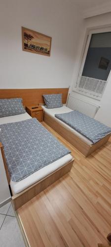 two beds in a room with wooden floors at Csata Vendéglő és Panzió in Isaszeg
