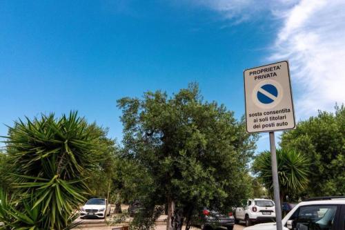a sign for a parking lot with cars and trees at La Dimora del Benessere in Noicattaro