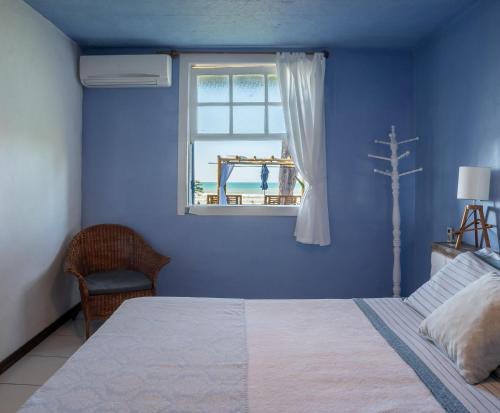 a blue bedroom with a bed and a window at Pousada dos Gravatás in Búzios