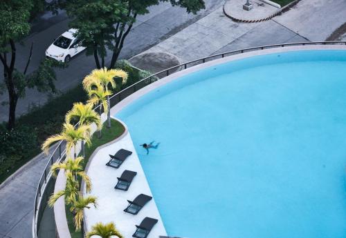 uma vista sobre uma piscina com cadeiras e palmeiras em Limketkai Luxe Hotel em Cagayan de Oro