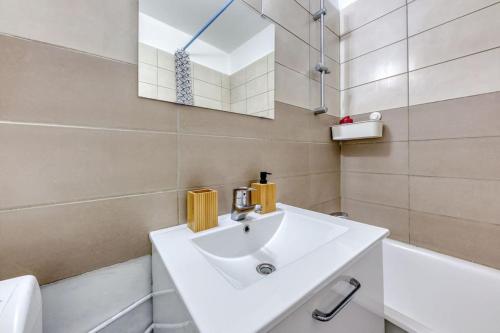 a white bathroom with a sink and a mirror at Réconfort - 15 min de Paris in Saint-Denis