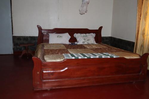 a bed with a wooden frame in a room at La Natura Guest House in Ruhengeri