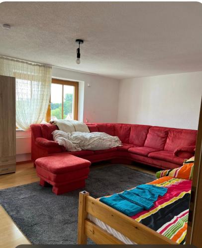 salon z czerwoną kanapą i łóżkiem w obiekcie Ganzes Haus in der Natur w mieście Lauingen