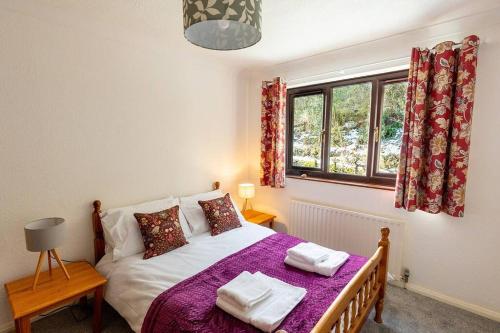 Un dormitorio con una cama con sábanas moradas y una ventana en UNDERWOOD COTTAGE - Peaceful House in Kendal with views of Cumbria, en Kendal