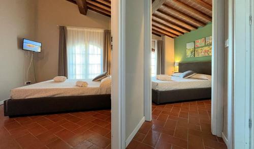a bedroom with two beds and a television in it at Borgo del Silenzio - Apartments with pool in Lajatico in Laiatico