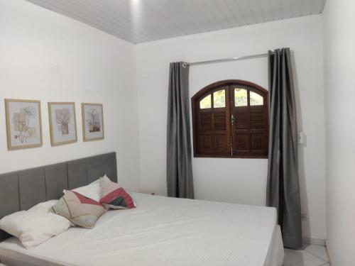 Schlafzimmer mit einem weißen Bett und einem Fenster in der Unterkunft Casa Rota dos Vales in Miguel Pereira